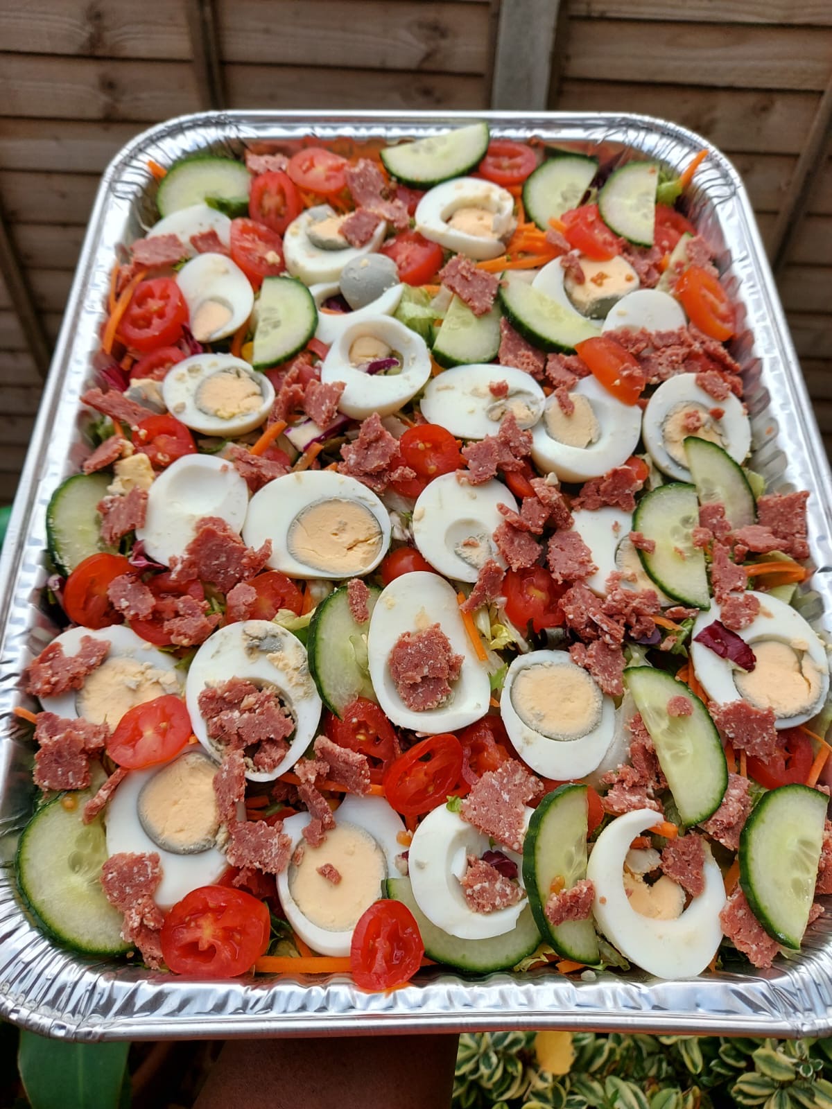 Large catering tray of fresh salad with boiled eggs, cucumber, tomato and corned beef